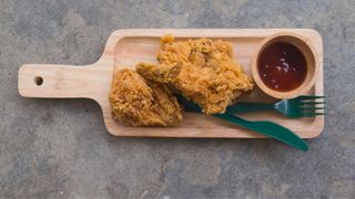 Fried chicken sitting on board with sauce