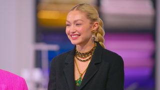 Gigi Hadid wearing green and gold necklaces and her hair in a plait