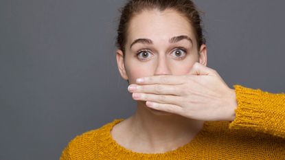 A woman holds her hand over her mouth.