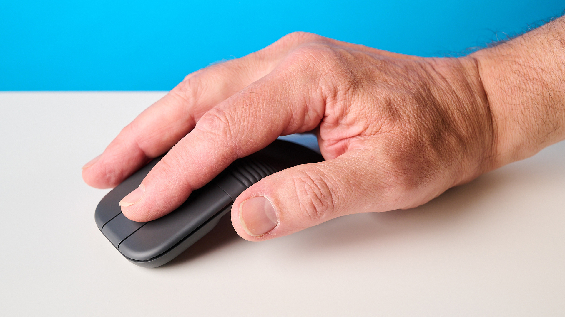 Logitech Mobi Fold mouse in graphite photographed in front of a blue background