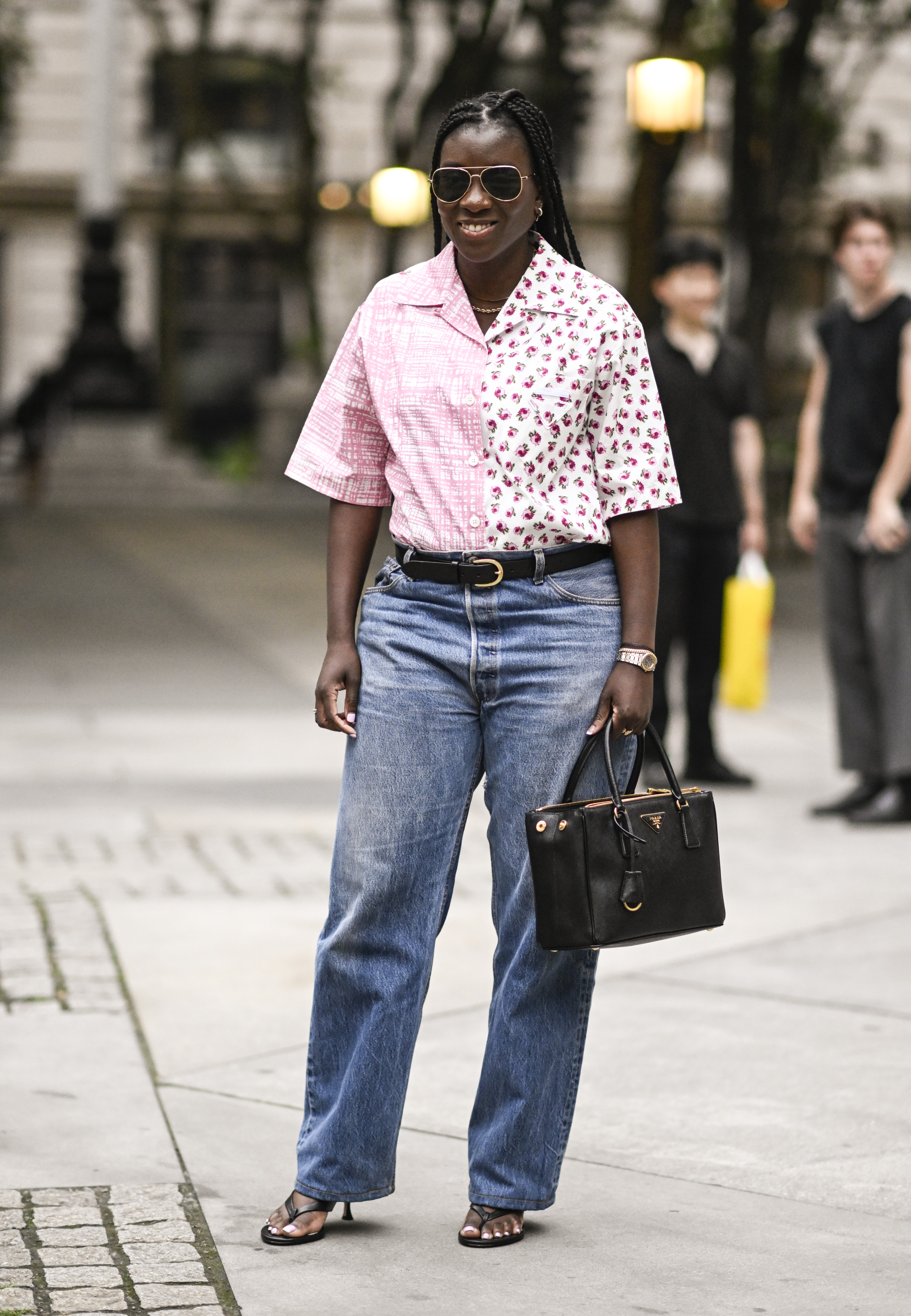 Nikki Ogunnaike is seen wearing a pink and white top, blue jeans, black belt, Prada belt and black and gold sunglasses outside the Marc Jacobs show on June 26, 2023 in New York City