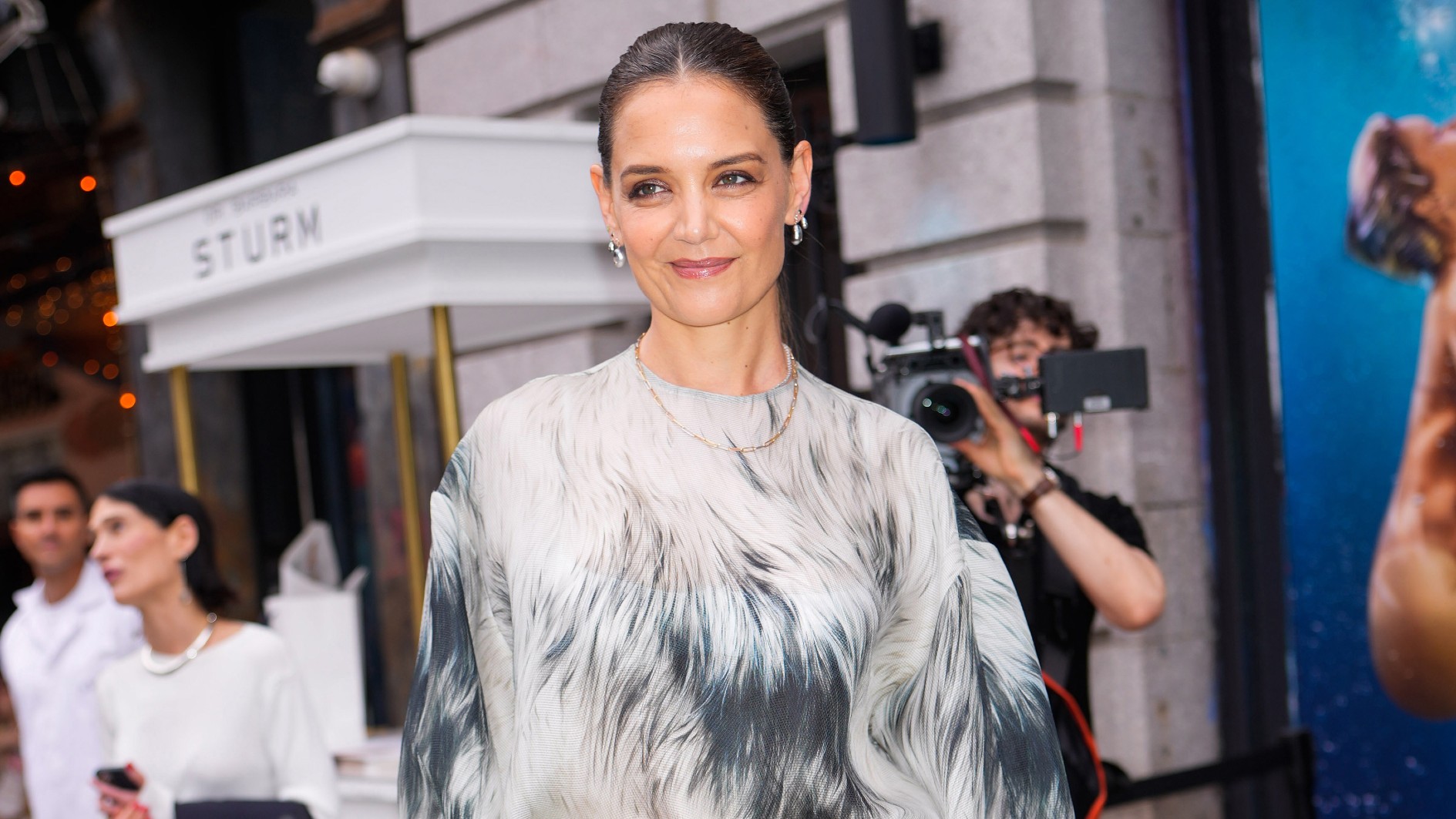 a woman in a faux fur printed blouse and black trousers being photographed by the paparazzi