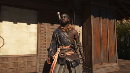 Assassin's Creed Shadows screenshot of Yasuke standing in front of the door to a building within a castle complex