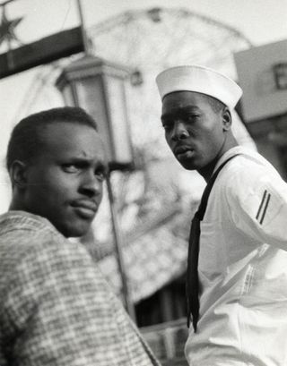 Black and white photograph of two black men turned towards the camera. One of them is dressed in a sailor’s uniform.