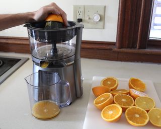 Camryn Rabideau using electric Cusinart juicer plugged into mains socket in kitchen to squeeze oranges