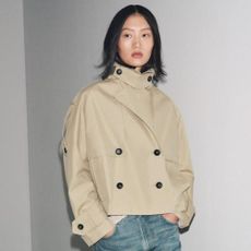 Woman wears beige trench coat and blue jeans
