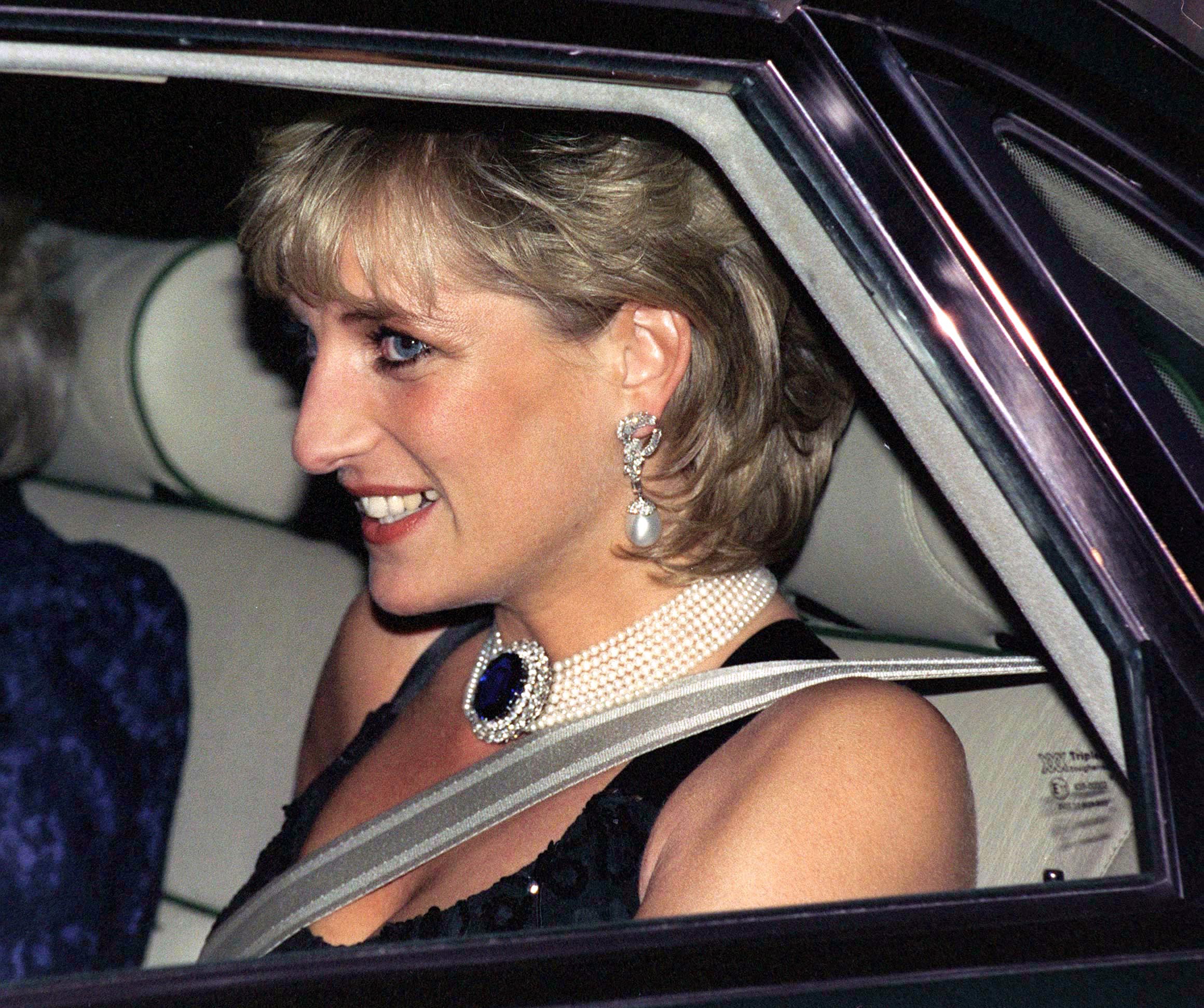 Princess Diana wearing a pearl choker and black dress sitting in a car