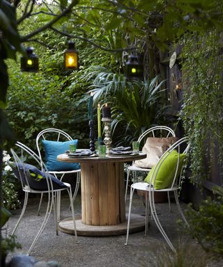 A small shaded patio area with a circular table and outdoor chairs