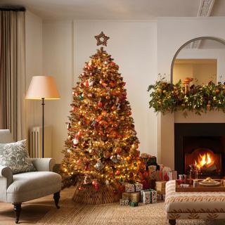 A decorated copper Christmas tree next to a fireplace