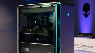 An Alienware Area-51 desktop PC lit up in blue and purple with the side of the case removed.