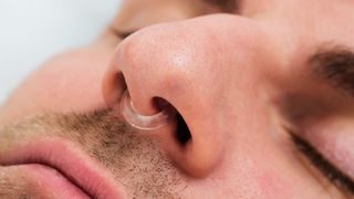 Ein Mann trägt eine Nasenklammer, um Schnarchen zu verhindern