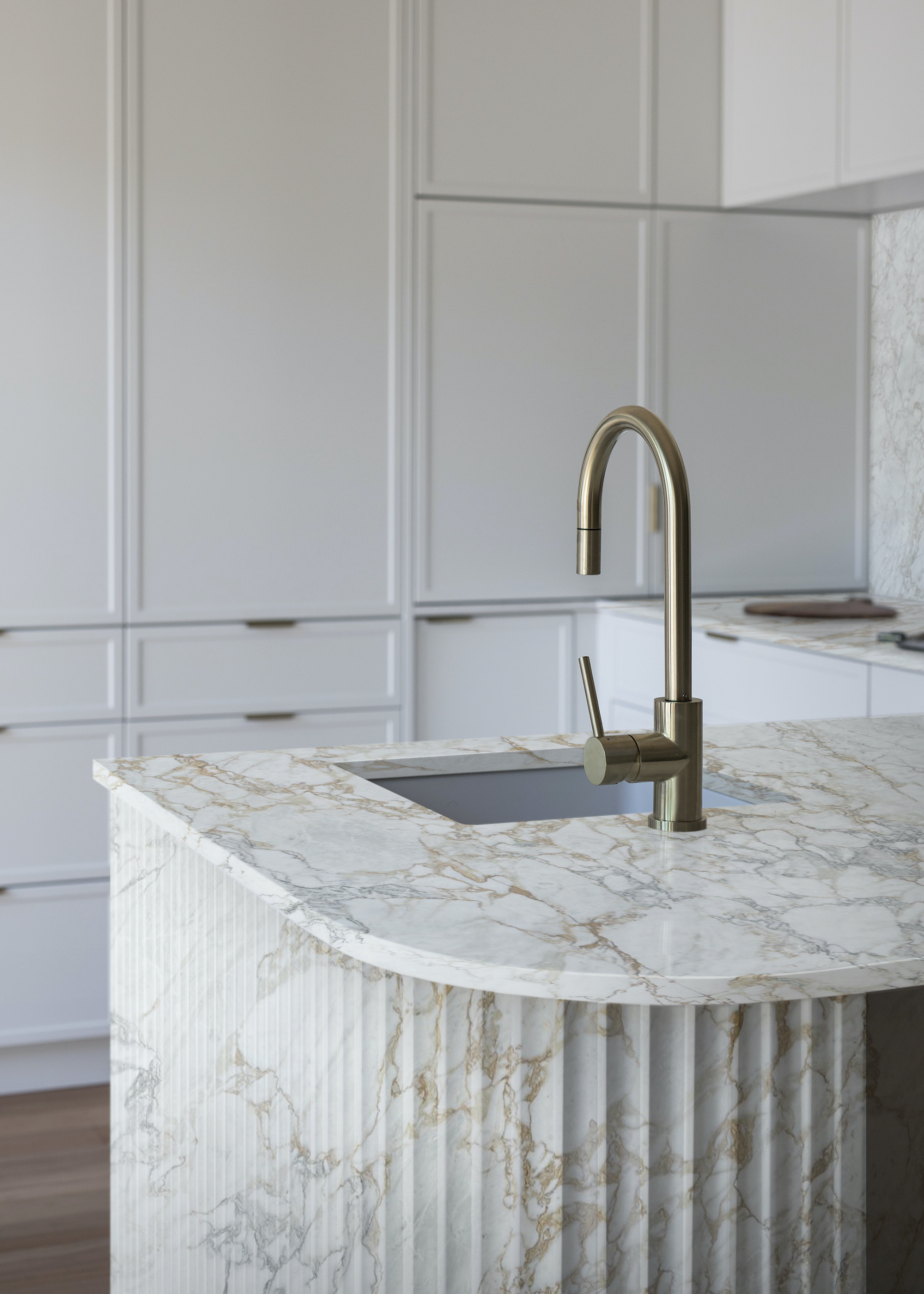 marble island with fluted sides and gold tap/sink on the island.