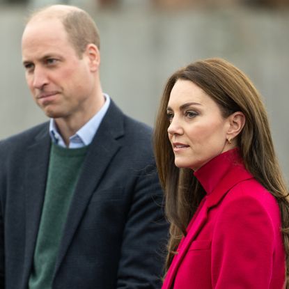 Prince William wears a navy coat and Kate Middleton wears a bright red coat and matching polo neck