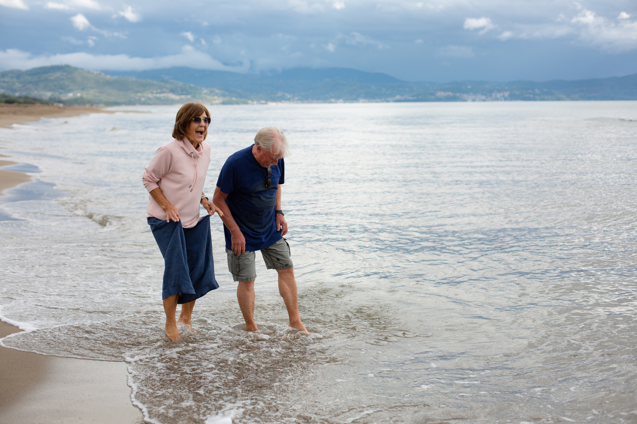 Older couple dipping toes in the ocean