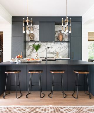 Dark gray kitchen in a period South Carolina beach house, with marble kitchen tile ideas and statement pendant lighting above a breakfast bar.