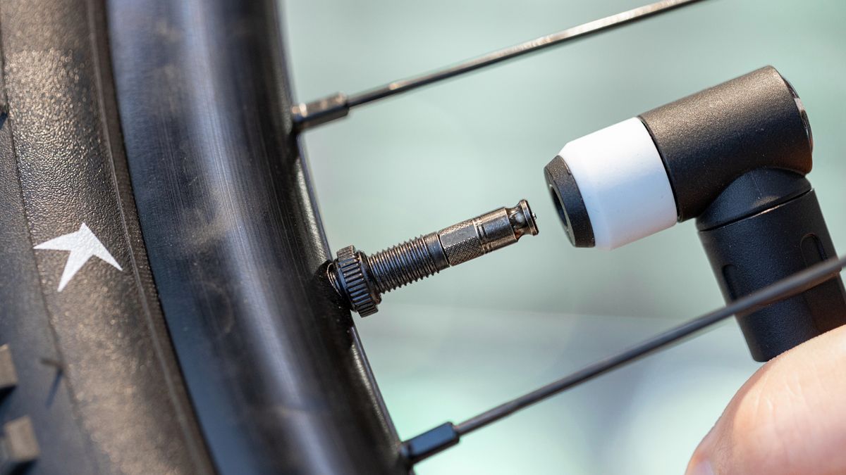 The Schwalbe Clik Valve stem on a wheel with a pump head about to be attached