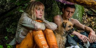 Daisy Ridley and Tom Holland in Chaos Walking sitting under some shelter with a pup named Manchee