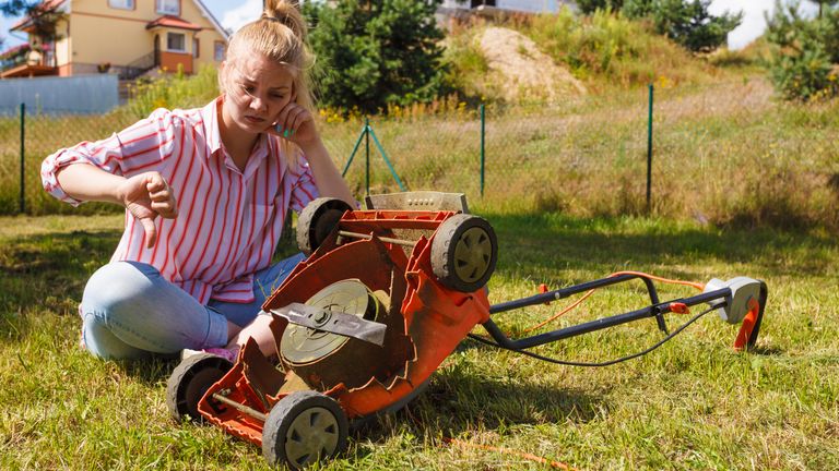 Woman looking sad after her lawn mower breaks