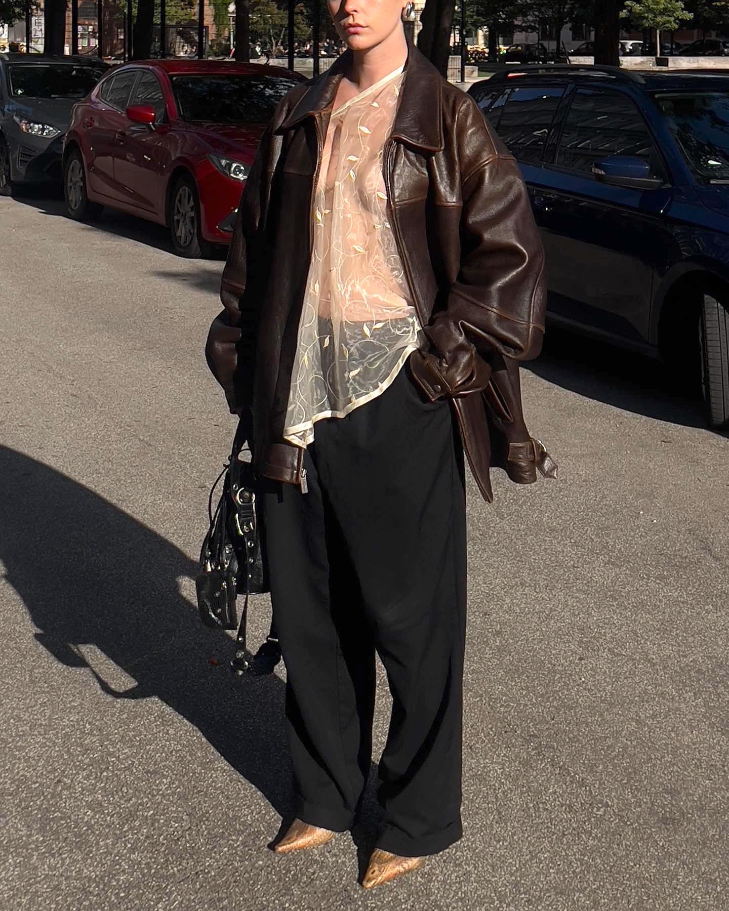 fashion influencer Brooklynn Gallagher wears a brown leather jacket sheer white top and black pants