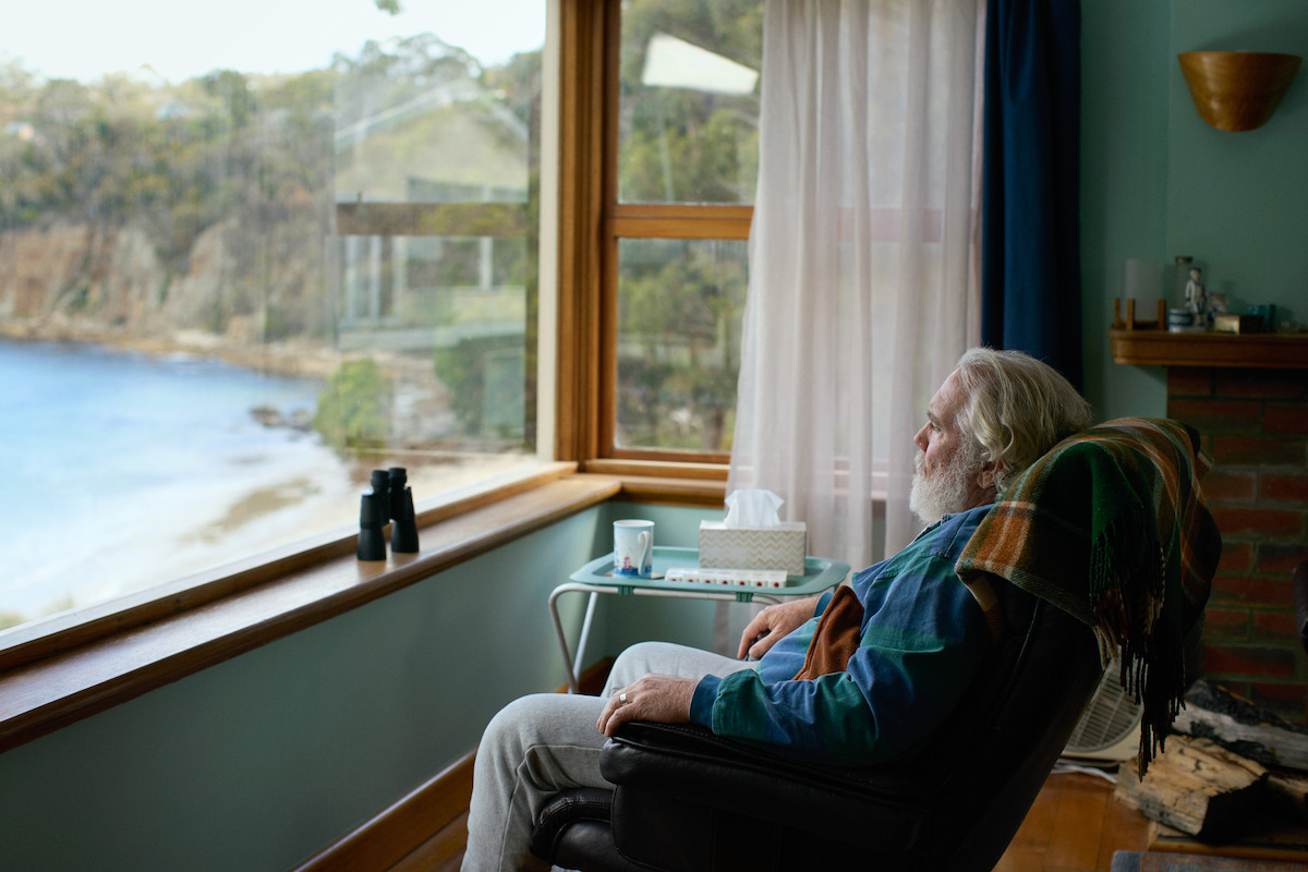 damien garvery as brian elliot sitting in a chair overlooking a beach in the survivors