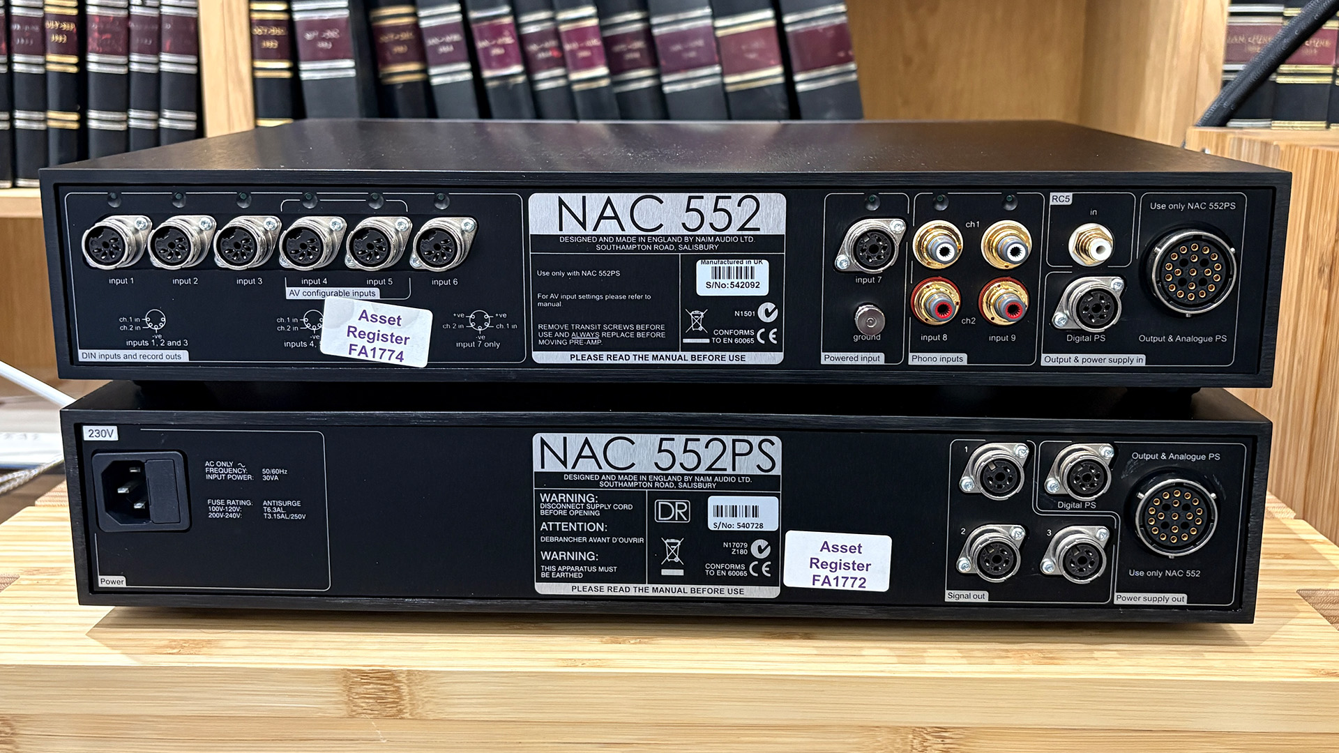 Naim NAC 552 pre amplifier on wooden hi-fi rack in front of bookcase, rear of units showing connections