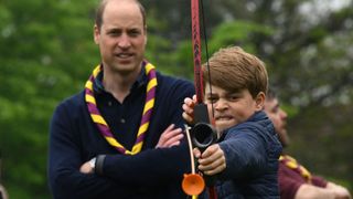 Prince William watches Prince George shoot a bow and arrow
