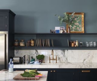 kitchen with muted blue walls and dark blue cabinets, white marble countertops