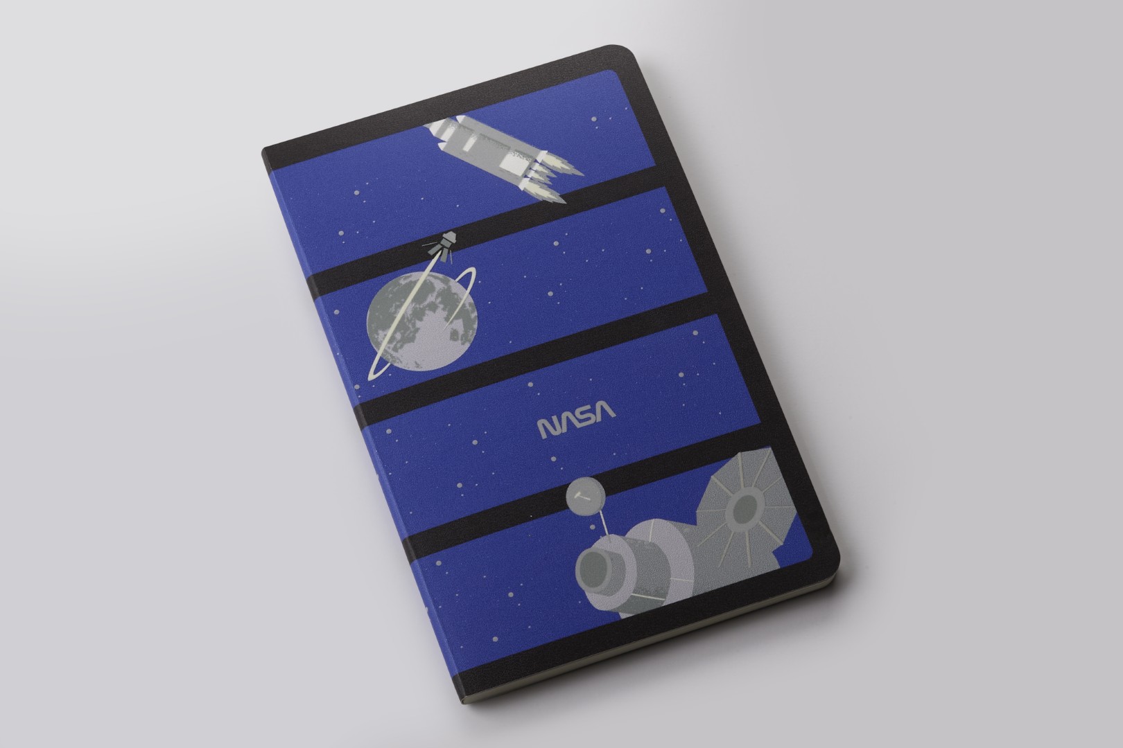 Softcover Volant Journal from the collection of NASA-inspired Limited Edition Notebooks from Moleskine. There are four dark blue panels in a column, each with it's own grayscale image. From top to bottom: rocket, Earth with orbiting satellite, NASA text, big satellite.
