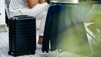 A close-up of a black carry-on hardshell suitcase with eight wheels. 