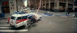The Ecto-1 speeding through New York City with a figure firing a proton pack in the gunner seat in Ghostbusters: Frozen Empire