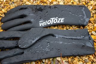 Velotoze neoprene gloves on some gravel with water droplets on them