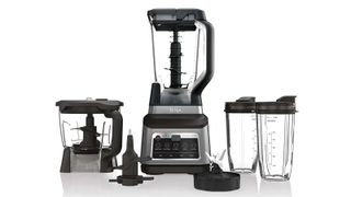 Ninja Professional Plus Kitchen System with Auto-iQ with two spare cups, a blender bowl and two mixer attachments next to it, one of the Ninja blenders on sale