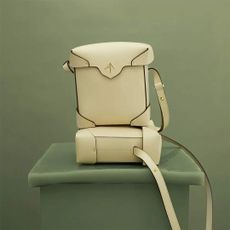 The mini pristine bag by Manu Atelier in creamy white sitting against a green background
