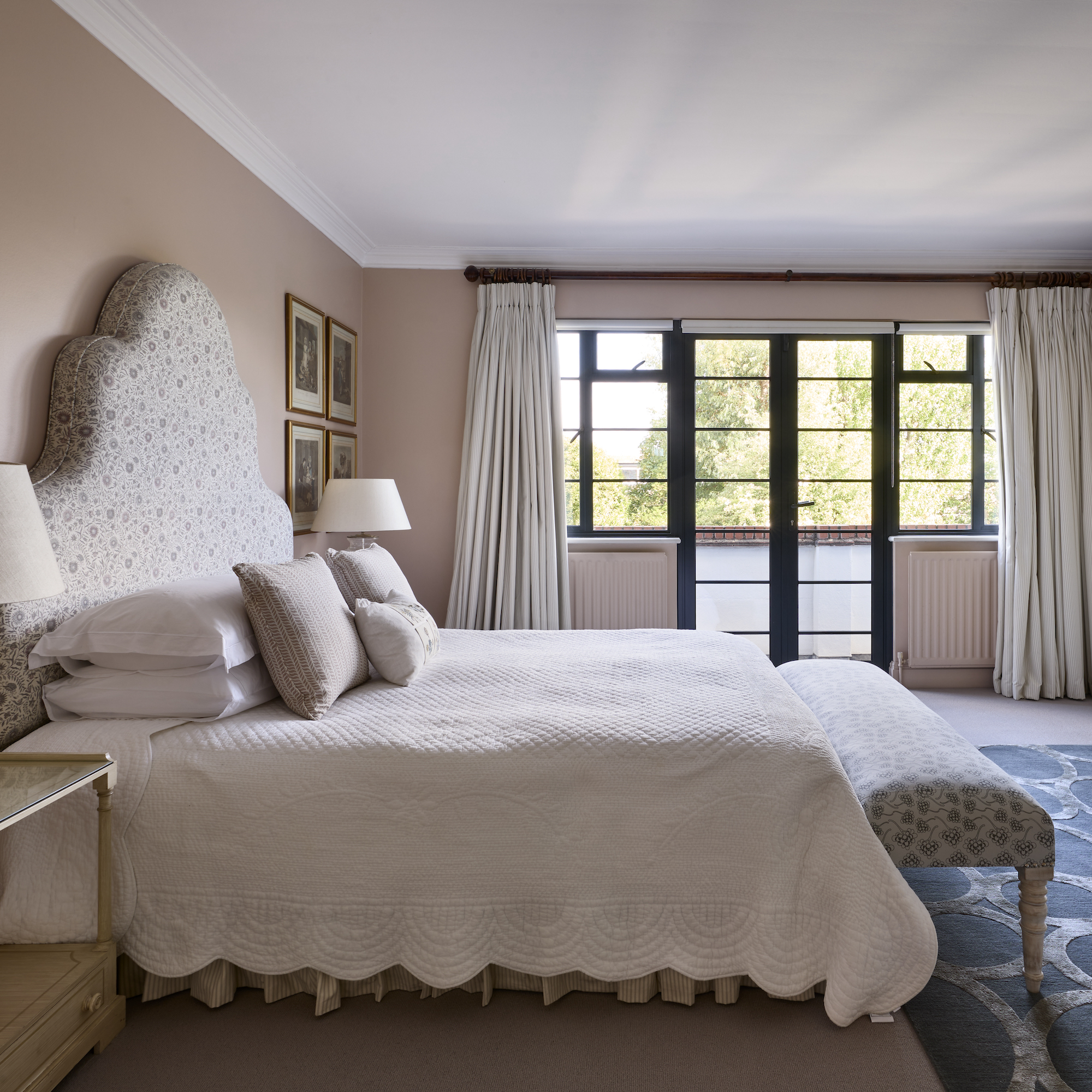bedroom with pink painted walls and oversized shaped headboard with crittall style patio doors