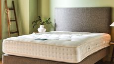 One of the best organic mattresses, the Woolroom Hebridean 3000 Mattress against a green wall.