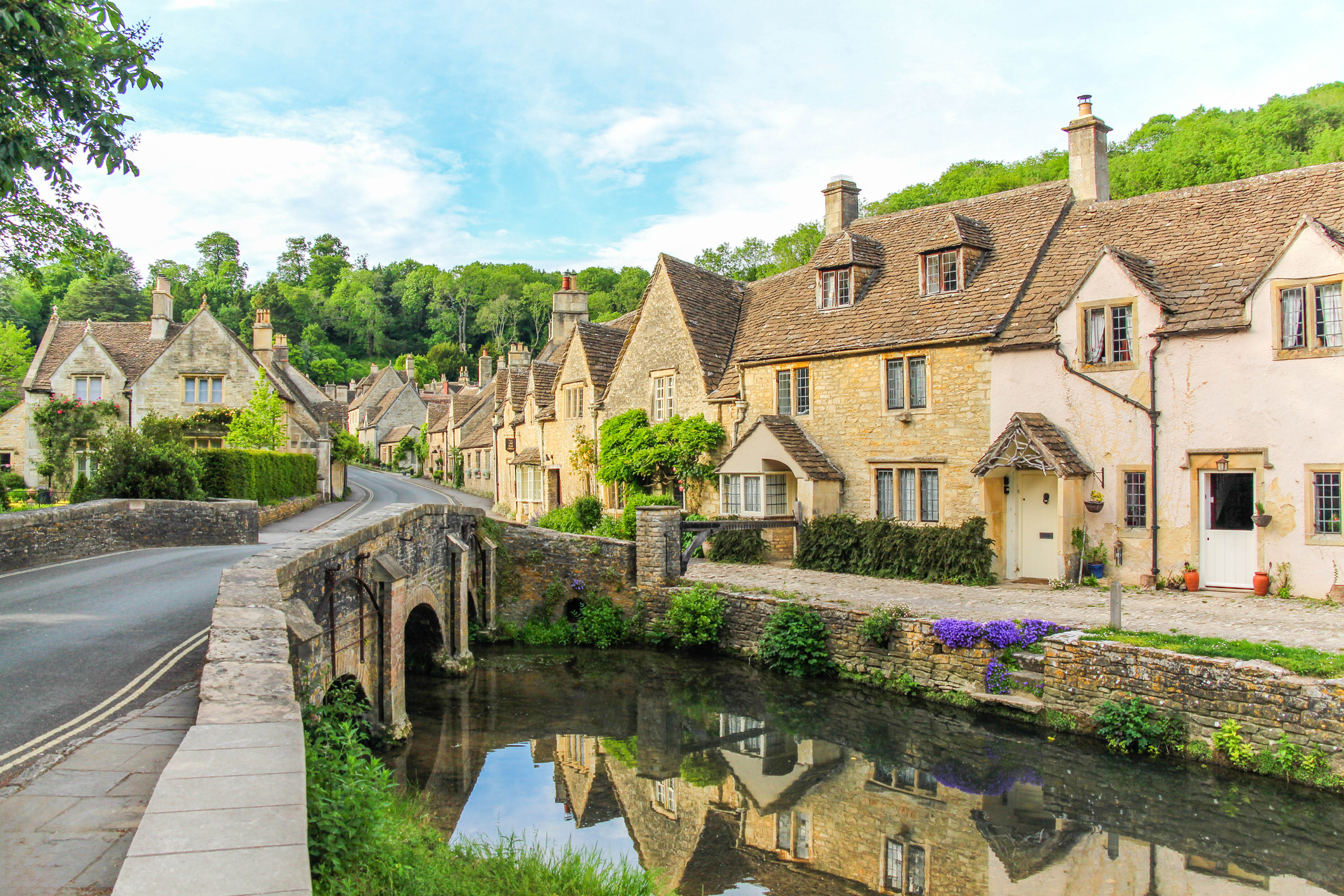 A picturesque view of cottages with Cotswold stone walls in Castle Combe, Cotswolds, England.