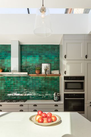 grey kitchen units surrounding green splashback tiles