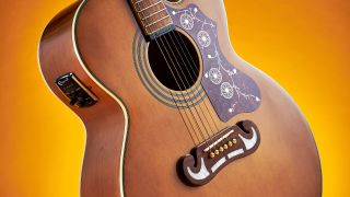 An Epiphone J-200 acoustic guitar on a bright yellow background