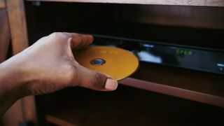 Person placing a blu-ray disc into a blu-ray player.