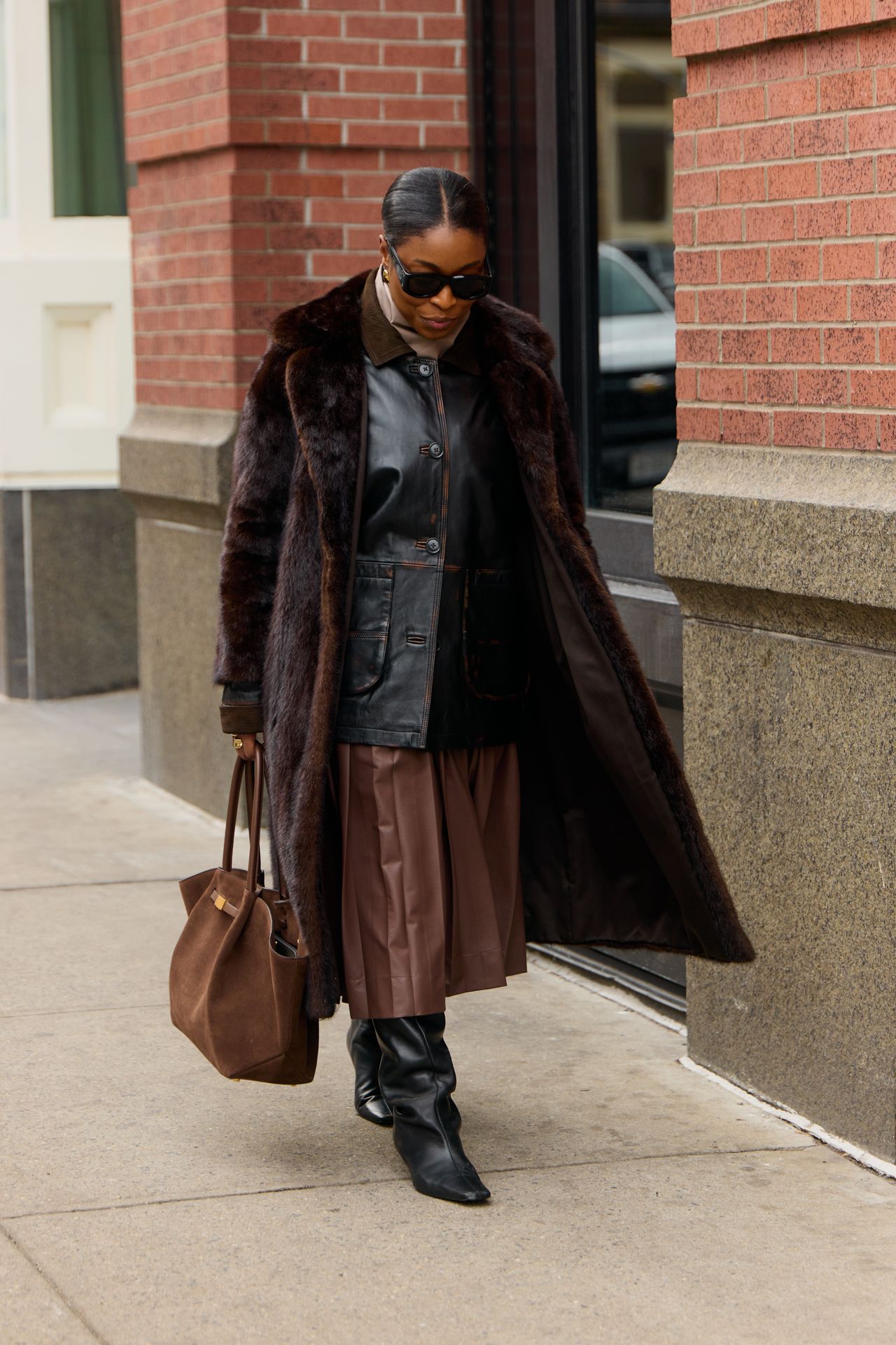 Cortne Bonilla wearing a leather blazer, brown leather skirt, and brown long fur coat during F/W 25 fashion week in New York.