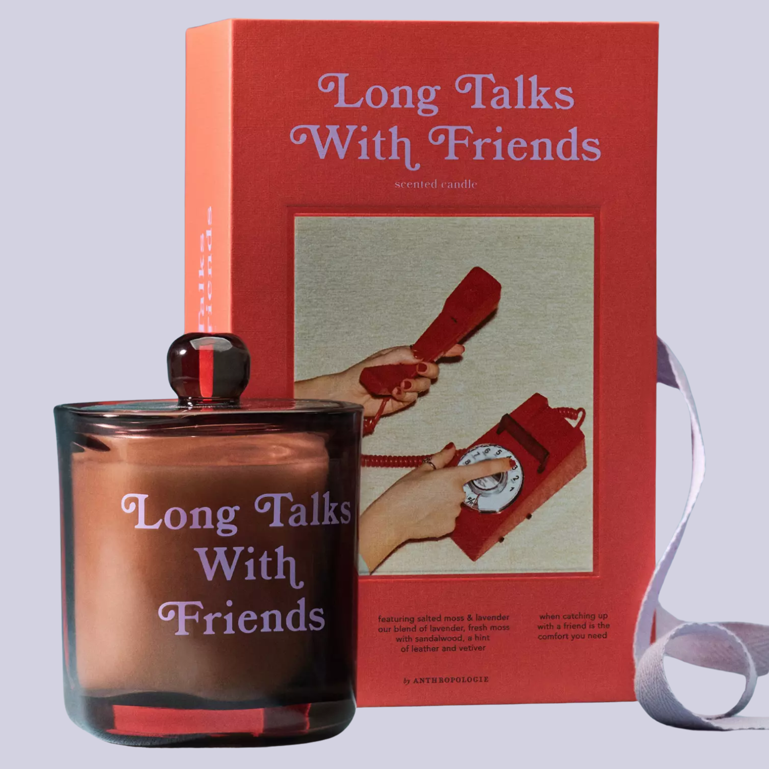 A glass candle with a lid beside an orange box