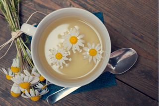 A coup of chamomile tea with daisies floating on the surface