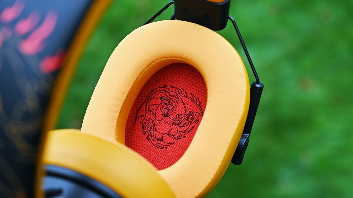 Close-up inside the yellow headset ear cushion, showing the red interior speaker fabric printed with a black line-art illustration of Charizard.