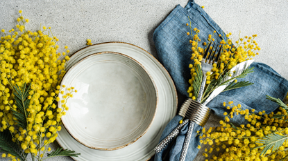 Overhead view of a place setting with yellow mimosa flowers on a table