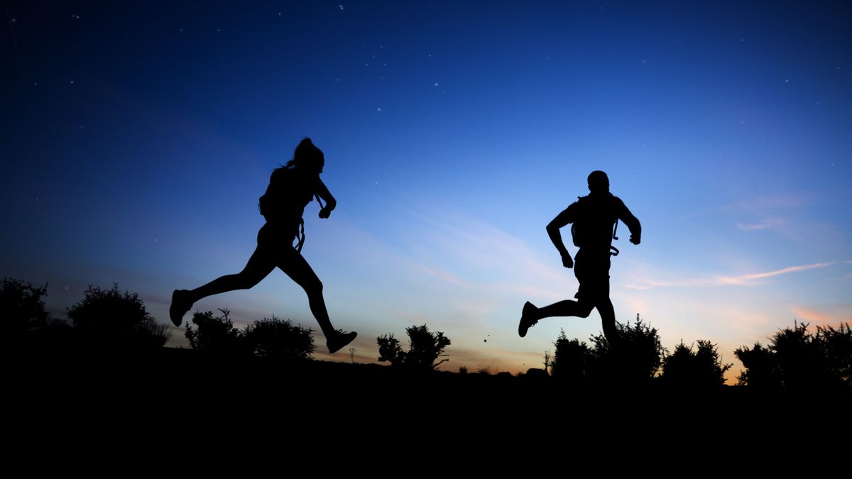 Silhouette of couple running at dawn