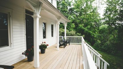 A long light wood porch with white fencing 