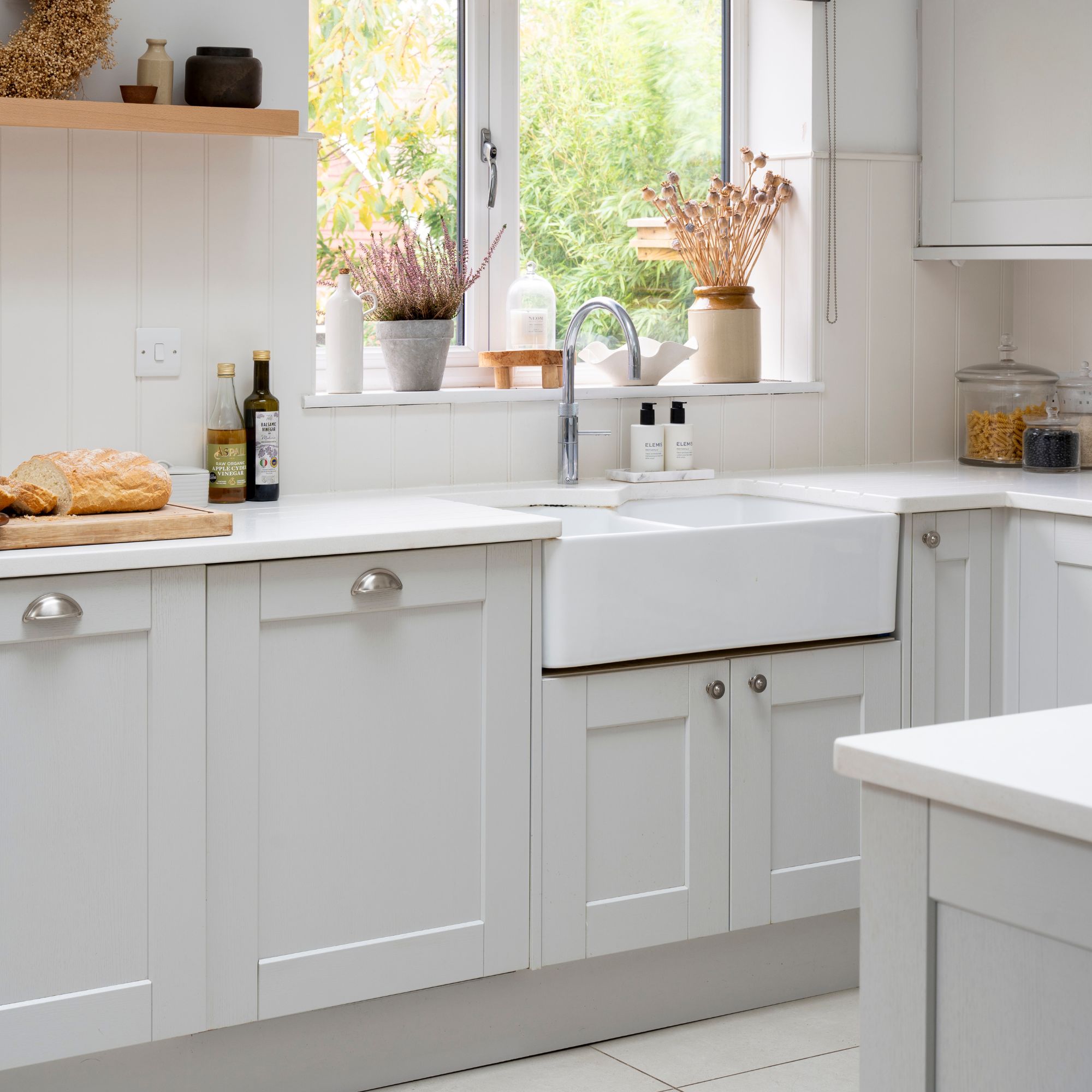 White painted kitchen with light grey cabinets and a white ceramic sink