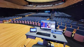 Several Extron solutions are mounted on a podium overlooking an empty auditorium ready for higher education.