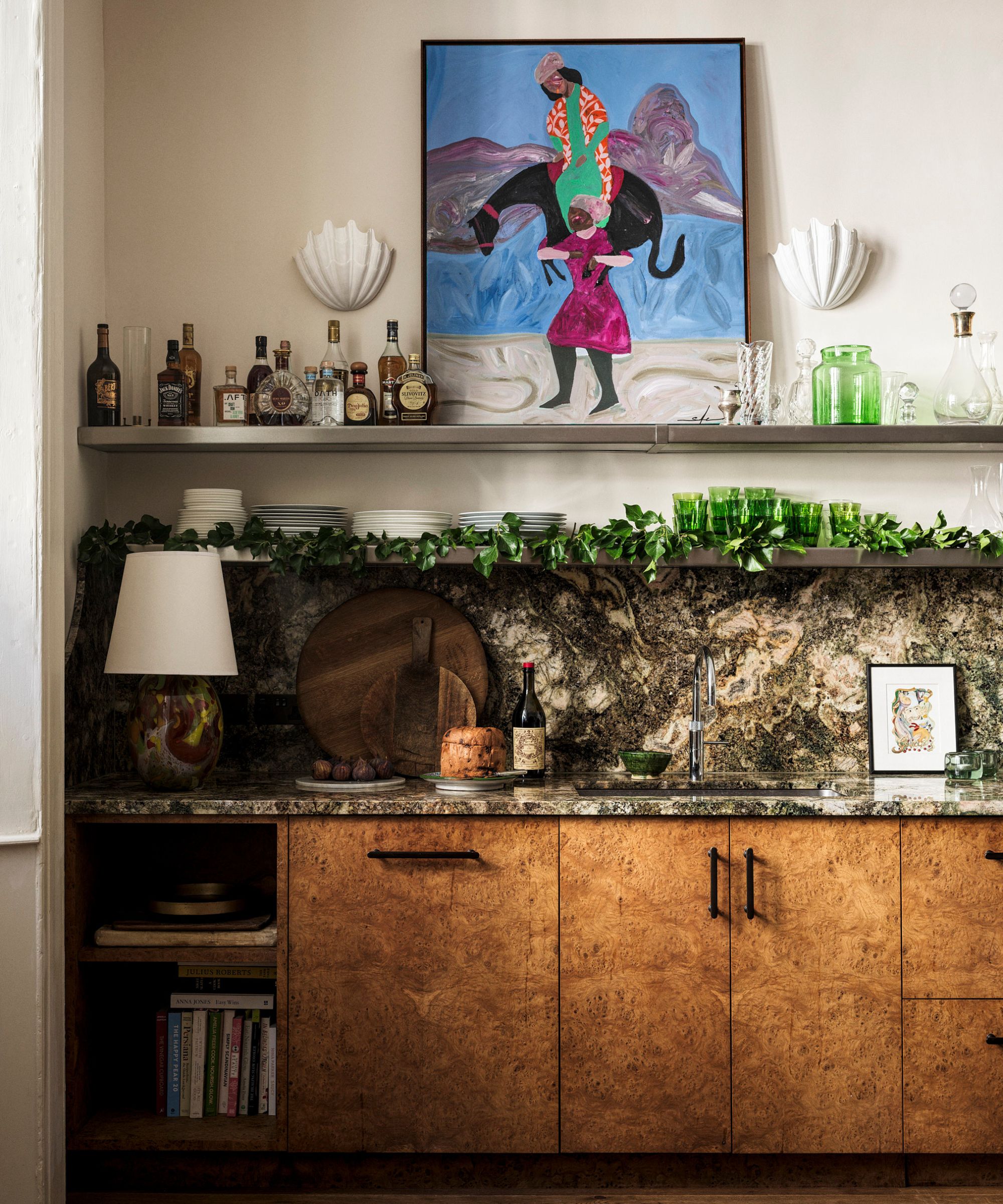 Counter with burl wood cabinets, stone backsplash, open shelving, and vibrant artwork