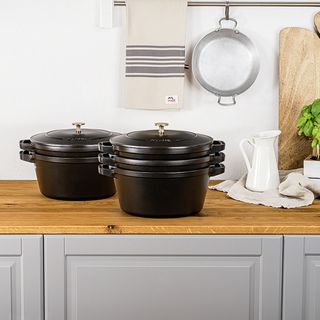 Staub dark grey cast iron cookware on a wooden worktop in a grey kitchen